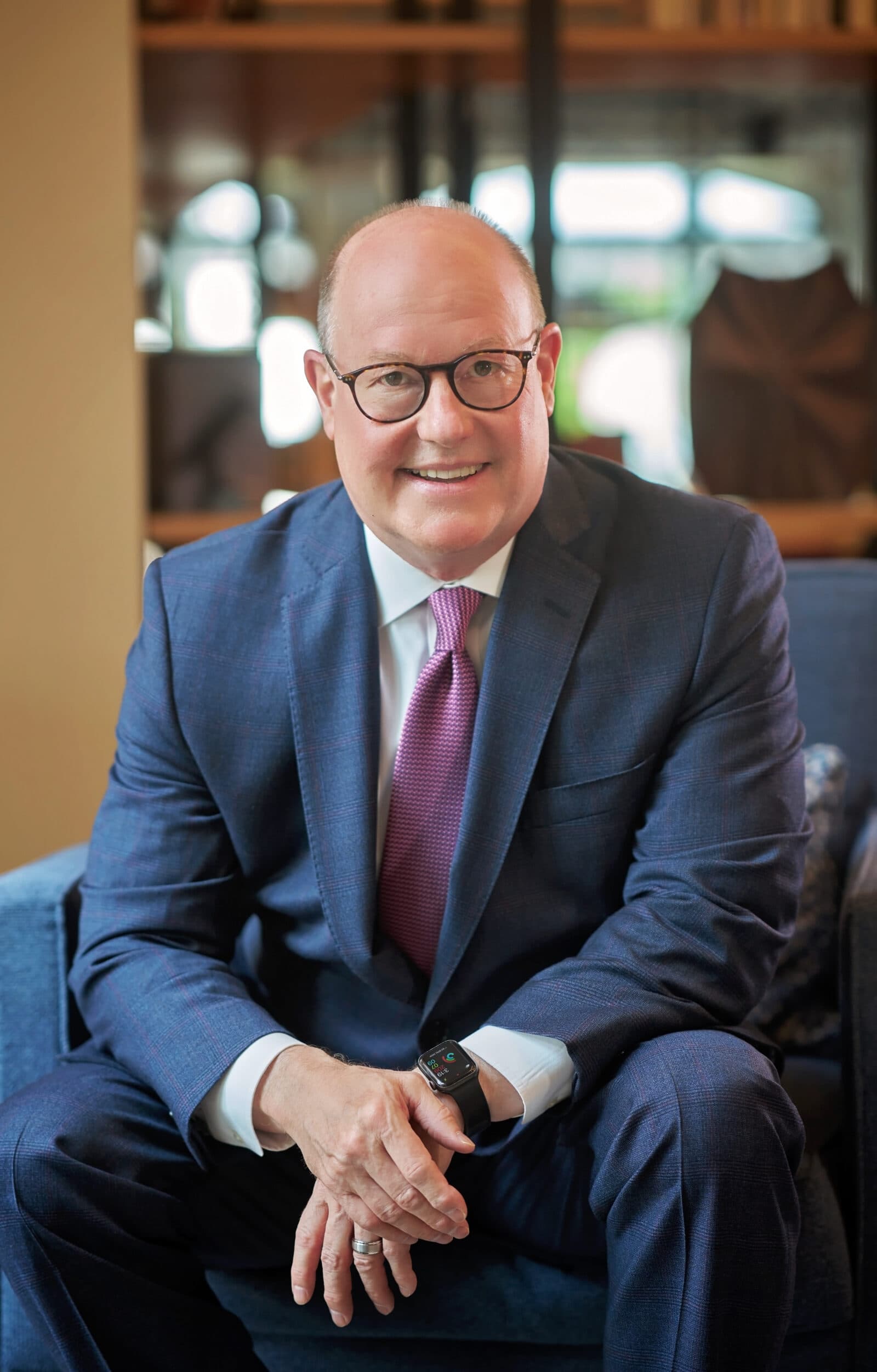 Preston is a bald white man in a gray suit and red / white tie. He is smiling at you.