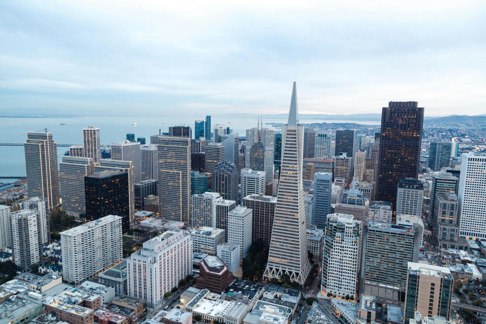 An aerial view of the skyline of San Francisco. The most prominent building in the image is the Transamerica Pyramid, a 853-foot (260 m) skyscraper that was completed in 1972. The Transamerica Pyramid is known for its distinctive triangular shape, which has become an iconic landmark of San Francisco.